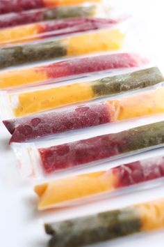 several popsicles are lined up on a white surface, each with different colored toppings