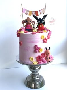 a pink cake decorated with cartoon characters and bunting