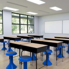 an empty classroom with desks and blue stools