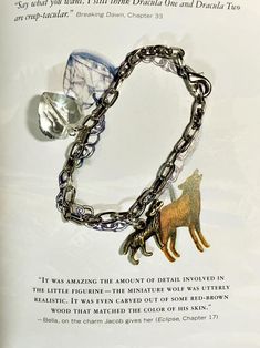 an open book with a chain attached to it and a dog charm hanging from the front