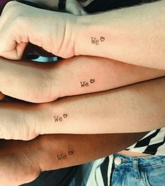 two people with matching tattoos on their arms, one holding the other's hand