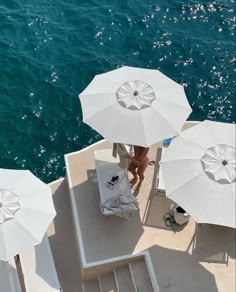 people are sitting under white umbrellas on the deck of a boat in the water