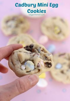 a hand holding up a cookie with chocolate chips and marshmallows