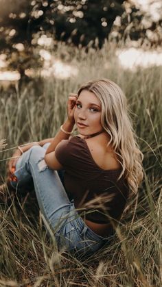 a beautiful blond woman sitting in tall grass