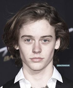 a close up of a person wearing a suit and tie with hair in the wind