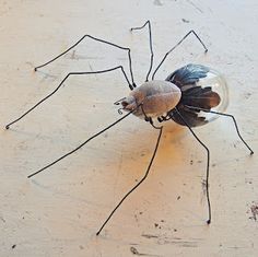 a large spider sitting on top of a white floor next to a glass jar filled with liquid