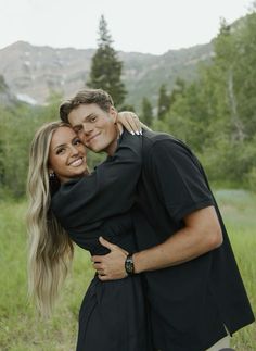 a man and woman hugging each other in the grass