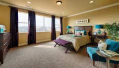 a bedroom with yellow walls and blue chairs in front of the bed is decorated with green plants