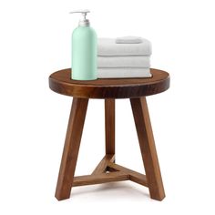 a wooden table with two white towels and a bottle on the top, sitting next to each other