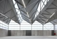 the interior of an empty building with high ceilings and concrete flooring is lit by bright lights