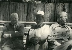 three men sitting on a bench wearing hats