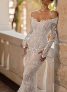 a woman in a wedding dress leaning against a wall