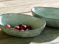 two bowls filled with fruit sitting on top of a wooden table