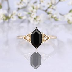 a black diamond ring sitting on top of a white surface with flowers in the background