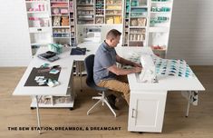 a man sitting at a white desk in front of a sewing machine on top of a wooden floor