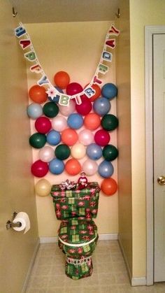 a bathroom decorated for christmas with balloons and presents on the wall, toilet paper roll wrapped in wrapping