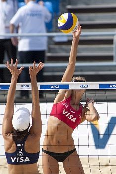 two women are playing volleyball on the beach