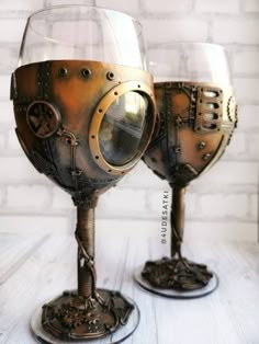 two wine glasses sitting on top of each other with steampunk design in them