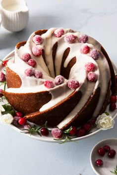 a cake with white frosting and raspberries sitting on top of a table