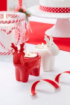 two red and white candles sitting on top of a table next to candy canes