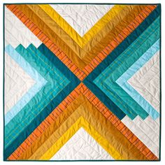 a quilted wall hanging on the side of a building with different colors and shapes