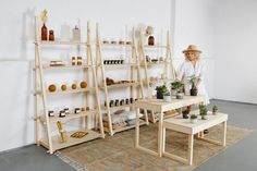 a woman standing in front of a shelf filled with potted plants and other items