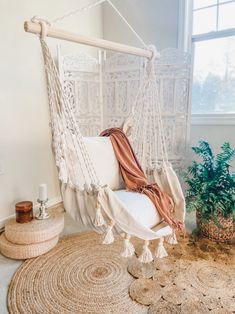 a hammock chair hanging from the ceiling in a room with rugs and potted plants