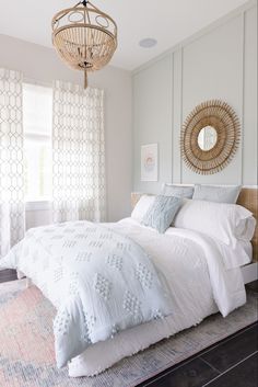 a bedroom with white bedding and a chandelier hanging from the ceiling above it