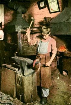 an old photo of a woman working in a wood burning oven holding a hammer and looking at the camera