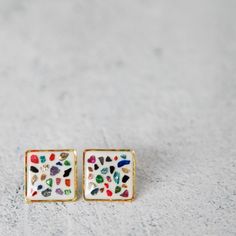 two small square shaped earrings with colorful designs on them