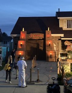 several people are standing outside of a restaurant at night with lights on the front door