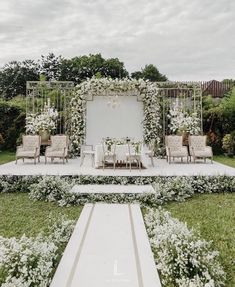 an outdoor ceremony setup with white flowers and greenery