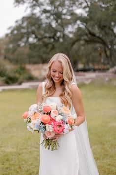 a woman in a wedding dress holding a bridal bouquet and smiling at the camera