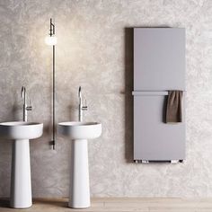 a bathroom with two pedestal sinks and a refrigerator in the wall next to each other