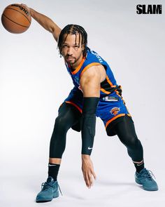 a man with dreadlocks holding a basketball in one hand and his right arm out