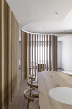 a long wooden table sitting in front of a wall with vertical slats on it