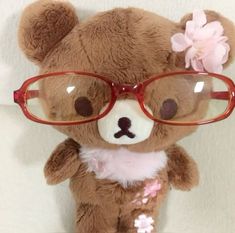 a brown teddy bear wearing glasses and a pink flower