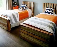 two beds in a room with wooden floors and blue walls, one has an orange blanket on it