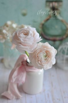 three pink flowers in a white vase on a table