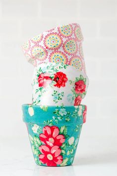 three flower pots sitting side by side on a white surface, each with different designs and colors