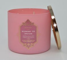 a pink candle with a gold lid next to it