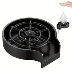 a black stove top sitting on top of a counter next to a hand holding an object