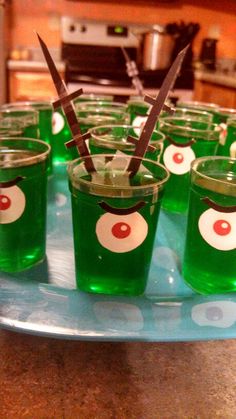 green shot glasses with scissors in them on a tray