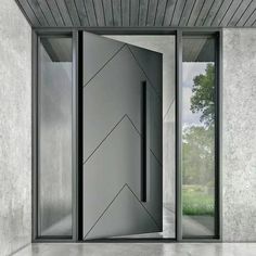 an open door in the middle of a room with concrete walls and floor to ceiling windows