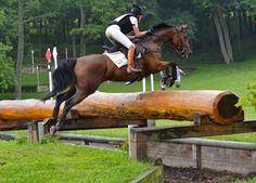 a person on a horse jumping over a log