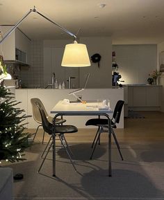 a dining room table with chairs and a christmas tree in the corner next to it