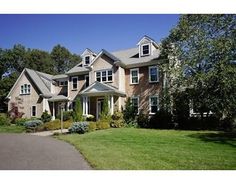 a large house sitting on the side of a lush green field next to a road