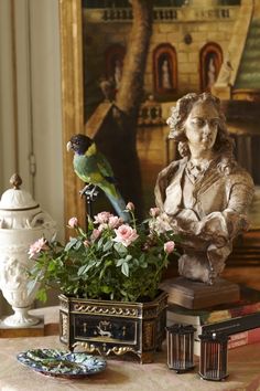 a bird sitting on top of a statue next to flowers