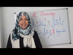 a woman standing in front of a whiteboard with writing on it and wearing a headscarf