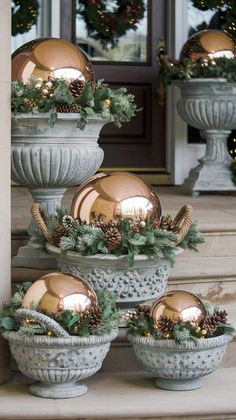 christmas decorations on the front steps of a house with gold balls and pine cones in them